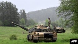 Американский солдат стоит на танке M1A2 Abrams Армии США во время учений Combined Resolve 18 на полигоне Хоэнфельс, на юге Германии. 11 мая 2023 г.