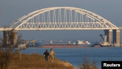 A Russian cargo ship is seen beneath a bridge connecting the Russian mainland with the Crimean Peninsula after three Ukrainian navy vessels were stopped by Russia from entering the Sea of Azov via the Kerch Strait in the Black Sea, Crimea November 25, 201